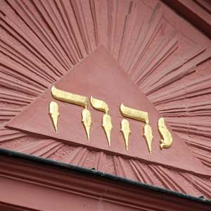 Der Gottesname JHWH in goldenen hebräischen Buchstaben auf einem Dreieck mit Strahlenkranz